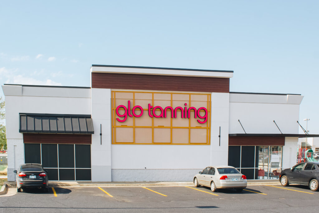 Glo Tanning storefront with parking (three parked cars are visible).