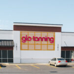 Glo Tanning storefront with parking (three parked cars are visible).