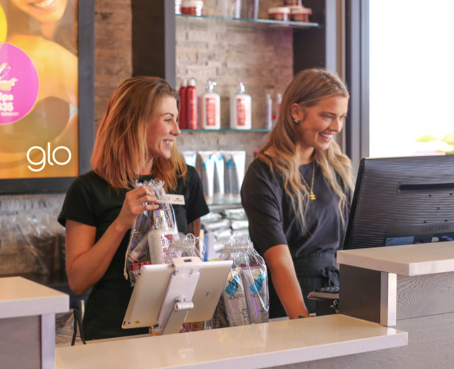 Two blonde glo tanning employees smiling.