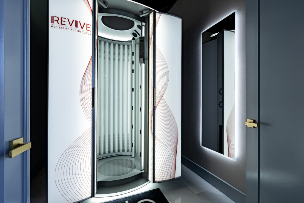 Full-body red light technology standing booth in a room with a window.
